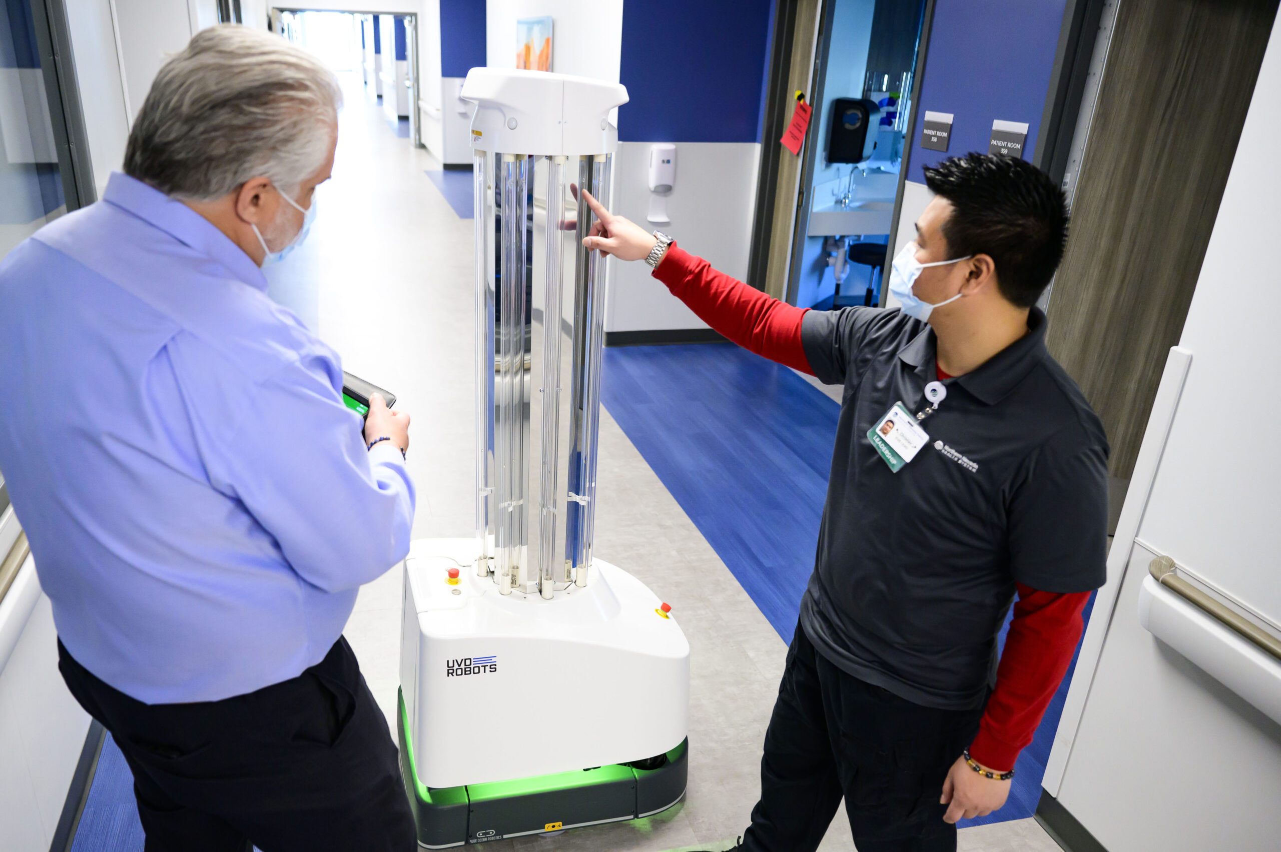 Man points to robot while other man observes