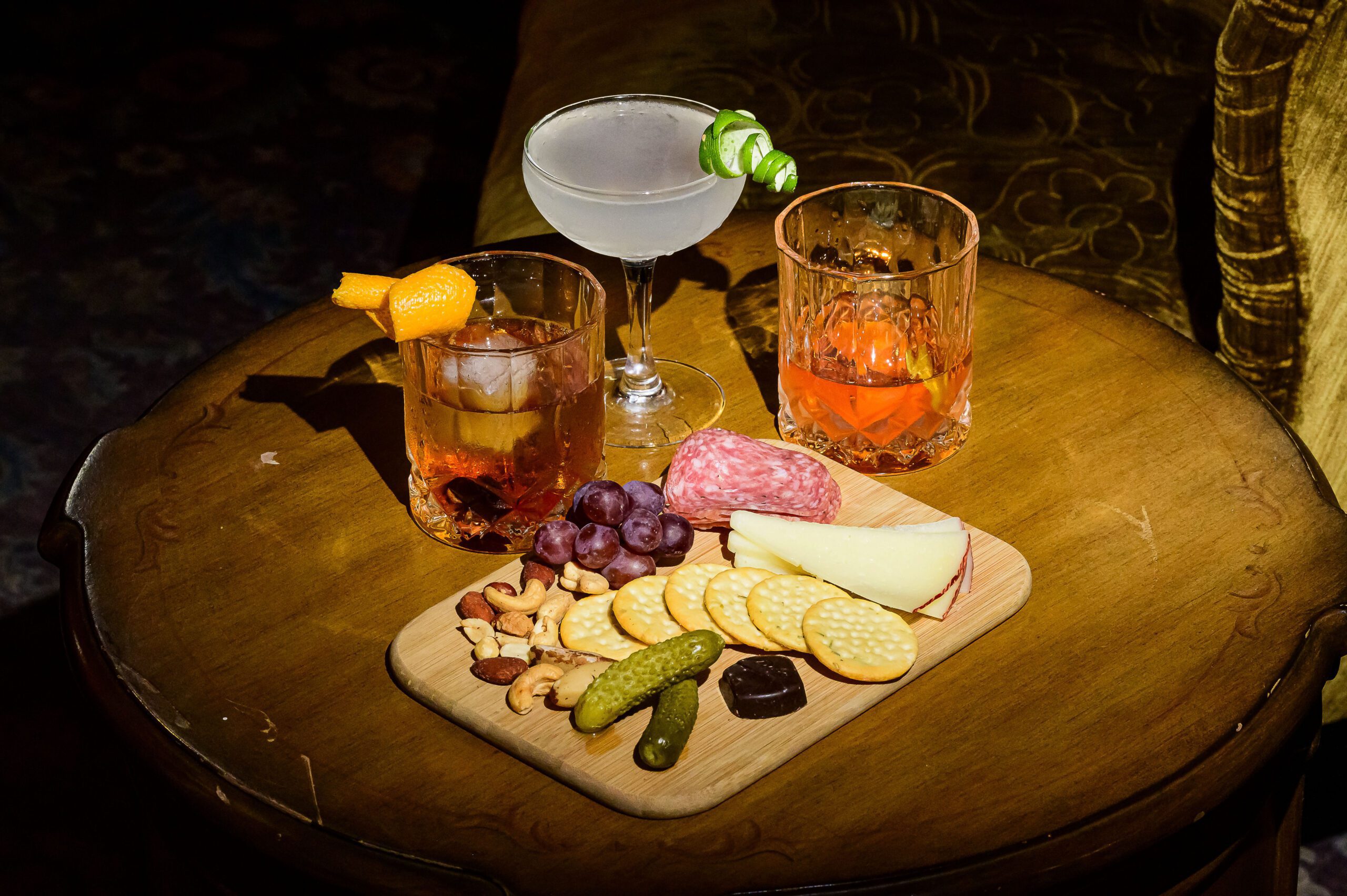 Table with three cocktails and a charcuterie plate