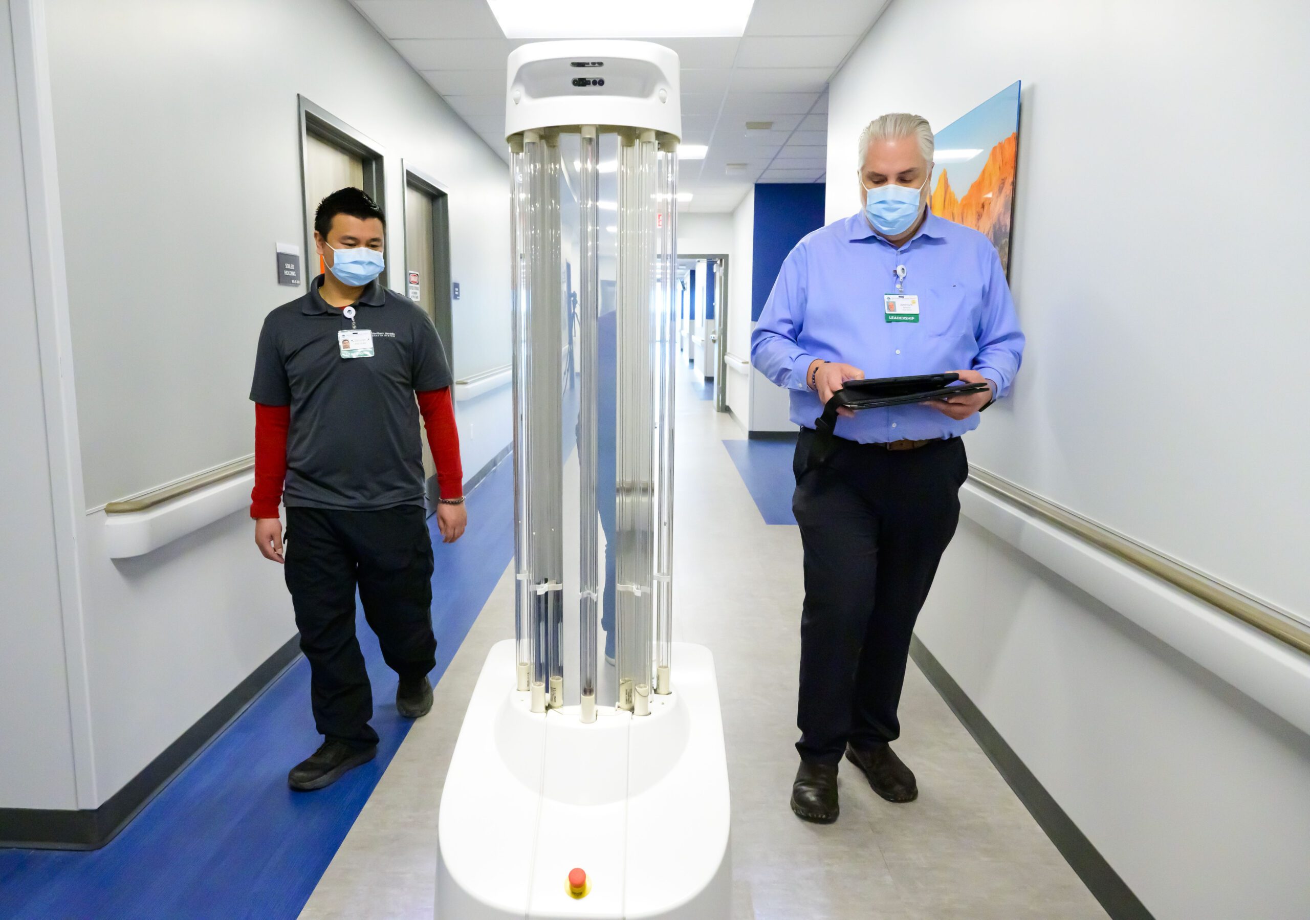 Two men walking in hallway with tall robot