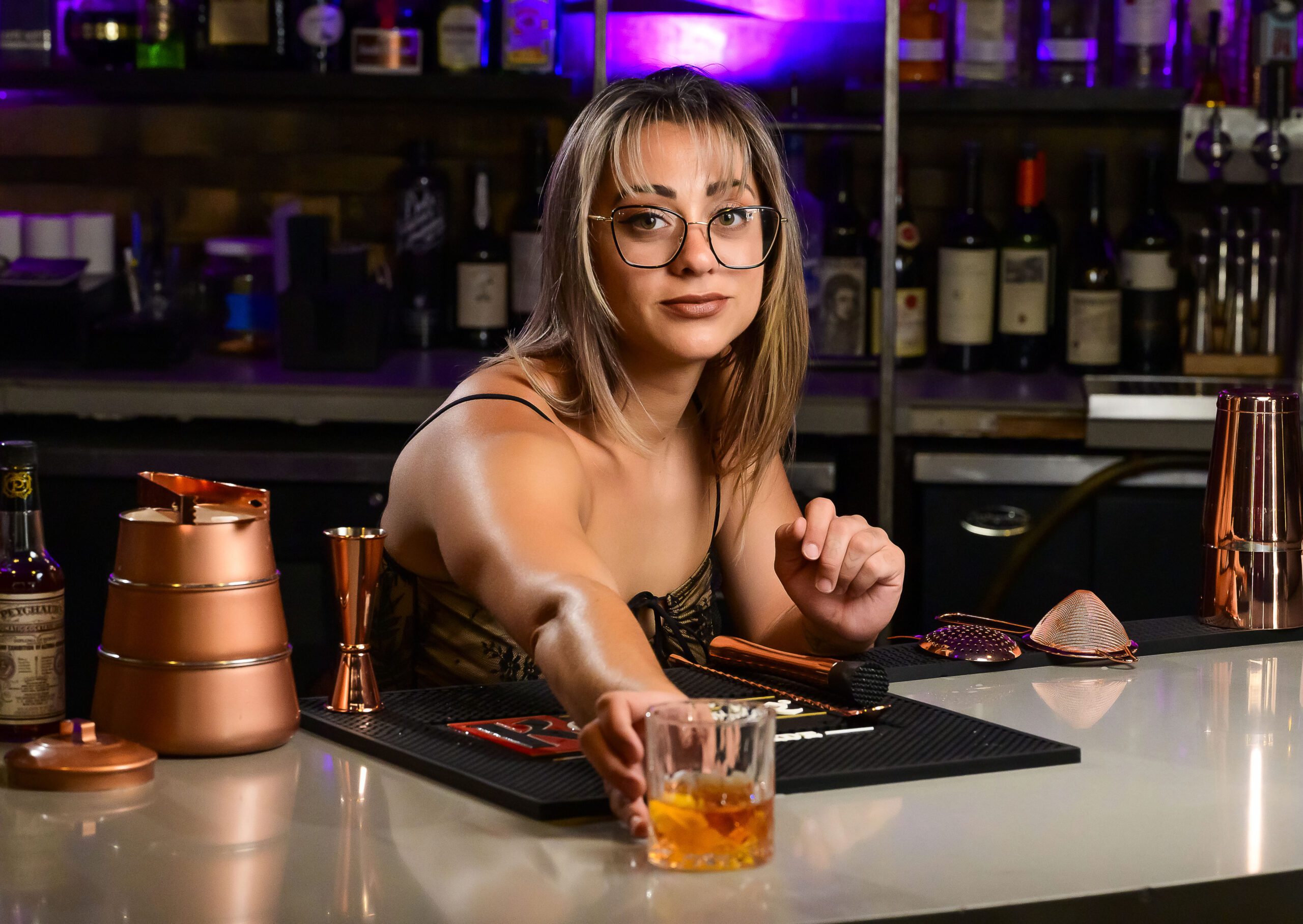 Woman pushing cocktail forward on a bar