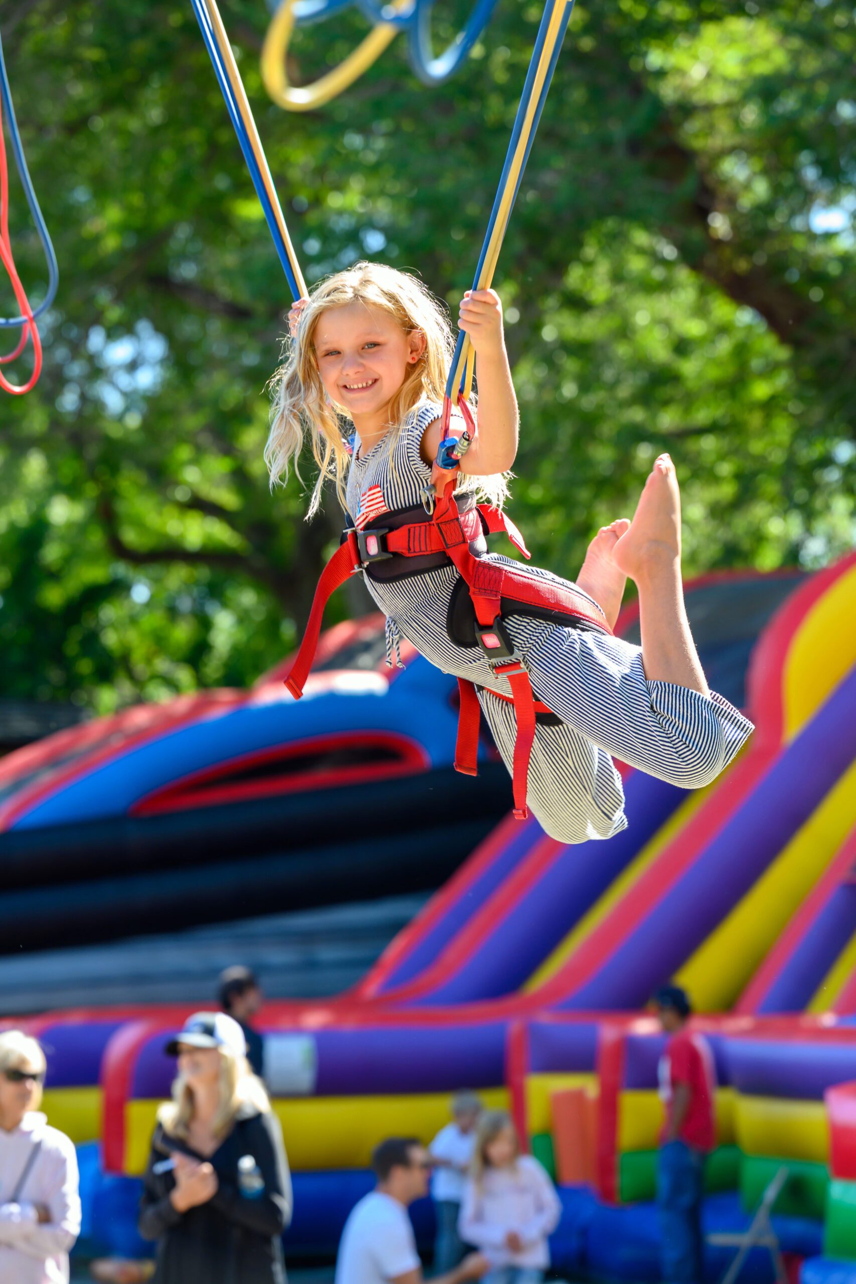 Child bouncing on trampoline while wearing a harness
