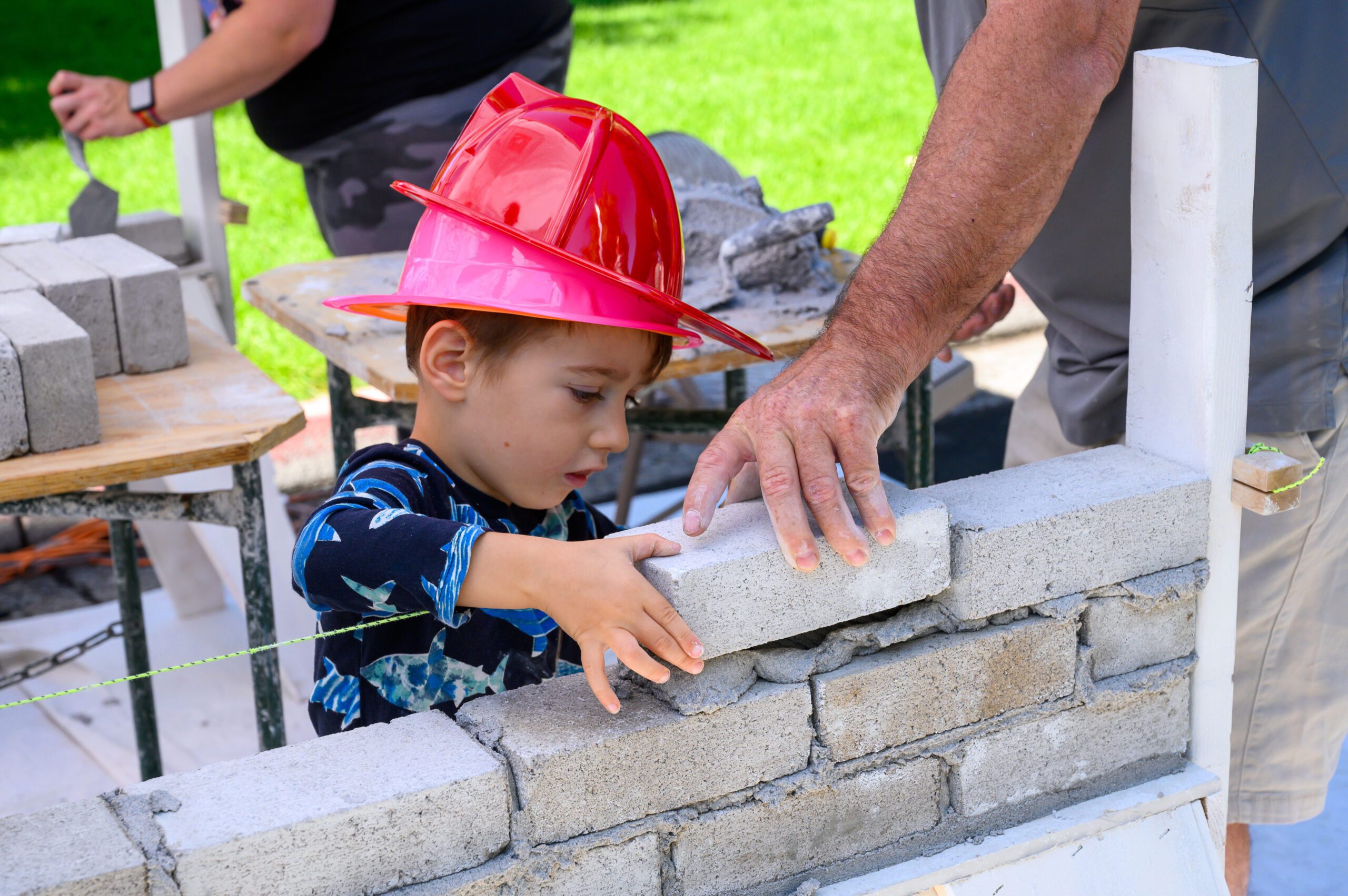 Child laying bricks with adult assistance