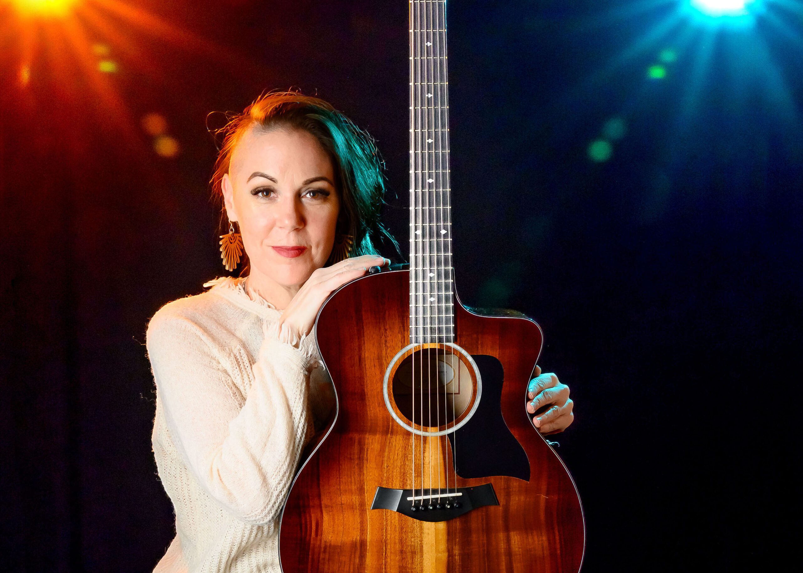 Professional photography of Woman sitting on a stool holding a guitar with colorful lights behind her