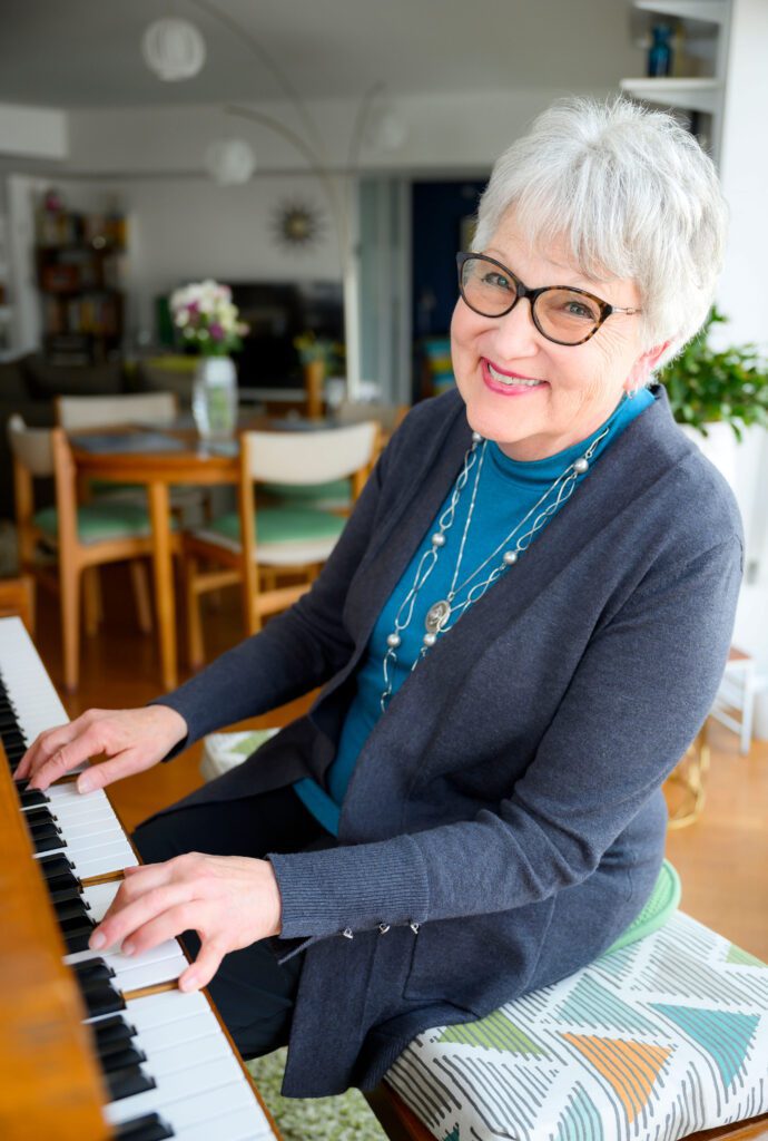 A woman sitting at a piano, smiling at the camera