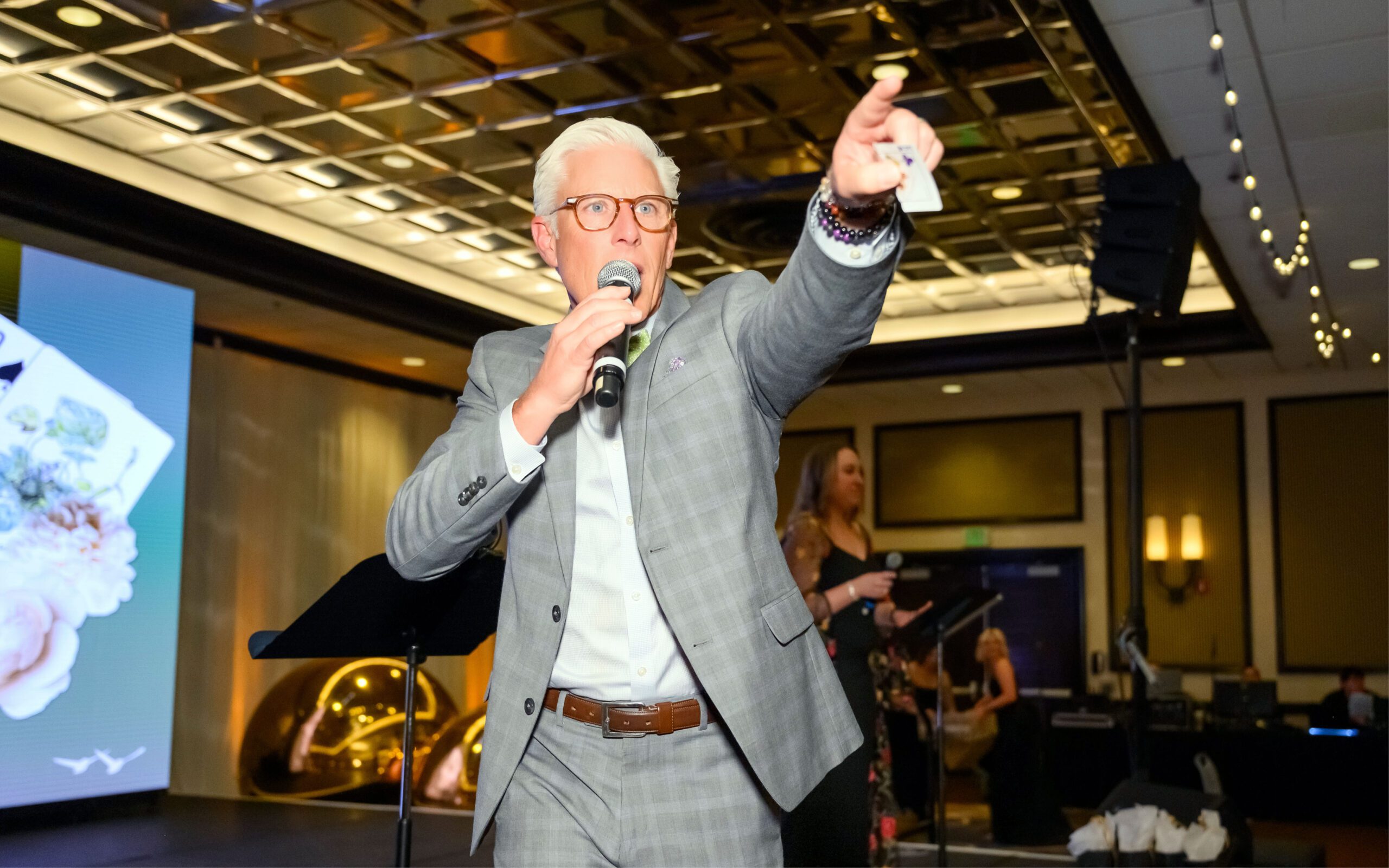 Man facing the camera points out at the crowd while holding a raffle ticket