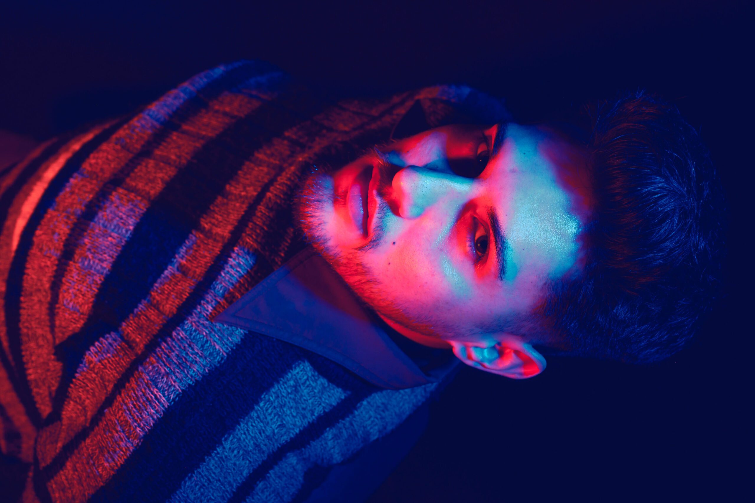 A woman sitting at a table with a paint brush in here hand. She is surrounded by paintings